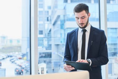 yakışıklı sakallı işadamı elbiseli ofiste dururken tablet PC'yi kullanma