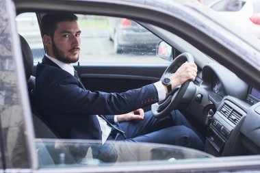 yakışıklı sakallı iş adamı arabaya oturan ve kameraya bakarak takım elbise 