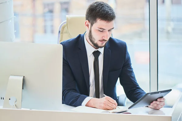 Ernstige Bebaarde Zakenman Schrijven Notitieblok Zittend Aan Tafel Met Computer — Stockfoto