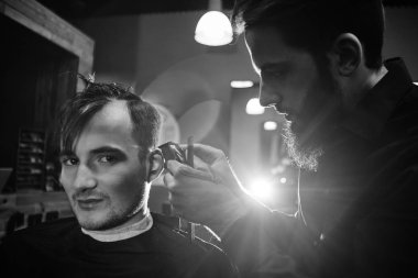 Kuaför müşteri berber dükkanı olarak kesme sürecinde siyah tişörtlü adam siyah ve beyaz fotoğraf