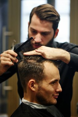 Kuaför müşteri berber dükkanı olarak kesme sürecinde siyah tişörtlü adam