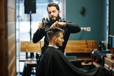 Kuaför müşteri berber dükkanı olarak kesme sürecinde siyah tişörtlü adam