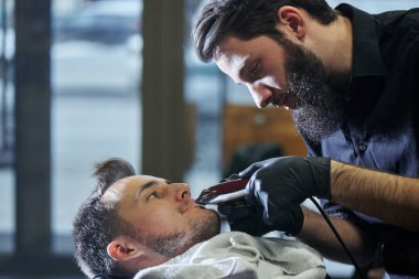 Kuaför müşteri berber dükkanı olarak kesme sürecinde siyah tişörtlü adam