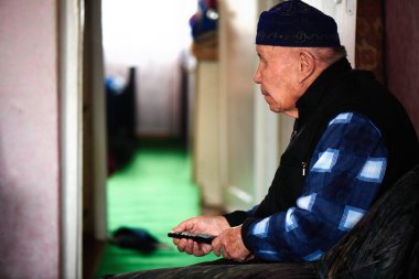 tv uzaktan kazak evde kanepede oturan ile Asya adam