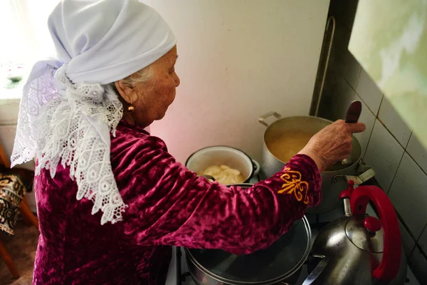 Kazašská Starší Žena Míchání Potravin Lžičkou Kastrolu Kuchyni — Stock fotografie