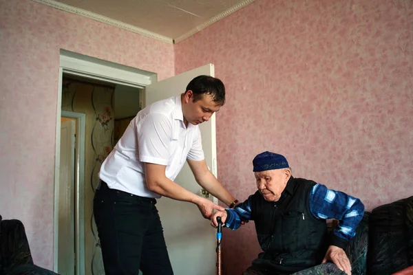 Nipote Aiutare Nonno Alzarsi Dal Divano Casa — Foto Stock