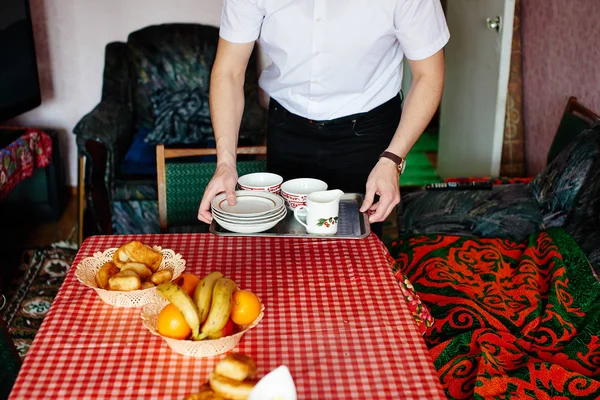 テーブルの上の食器と金属製のトレイを置く男 — ストック写真