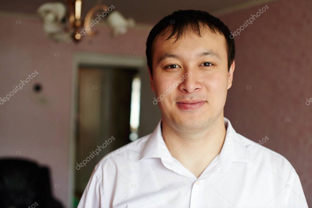 portrait of asian man wearing white shirt standing in Kazakh house