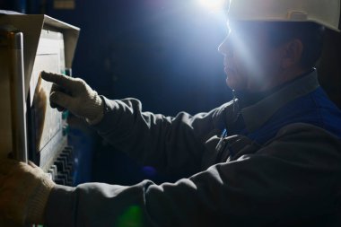 Kontrol panelindeki fabrika içinde ekipman erkek işçi tulumu ve kask presler