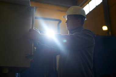 Kontrol panelindeki fabrika içinde ekipman erkek işçi tulumu ve kask presler