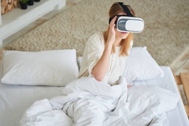 VR-gözlük kullanmasına ve yatağa evde otururken kadın 