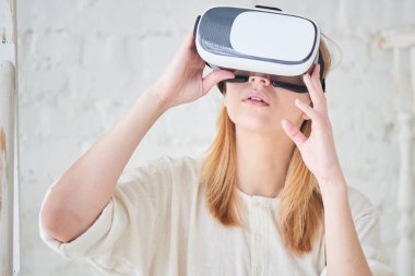 beyaz duvara yakın dururken VR-gözlük kullanan kadın 