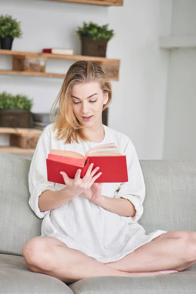 Mulher Sentada Sofá Lendo Livro Vermelho Casa — Fotografia de Stock