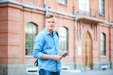 kot gömlek ve tablet pc Üniversitesi önünde duran süre tutan kot yakışıklı öğrenci 