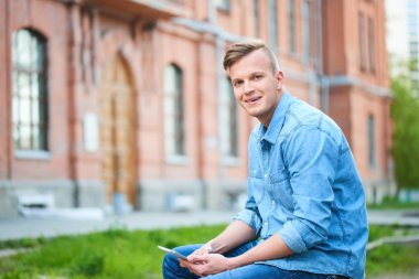 öğrenci üniversite güneşli gün oturan tablet pc ile kot gömlek 