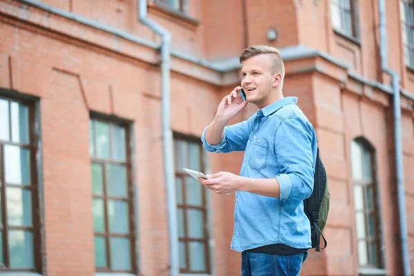 Estudiante Camisa Mezclilla Sosteniendo Tableta Hablando Por Teléfono Mientras Está — Foto de Stock