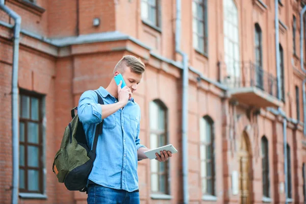 Estudiante Camisa Mezclilla Sosteniendo Tableta Hablando Por Teléfono Mientras Está — Foto de Stock