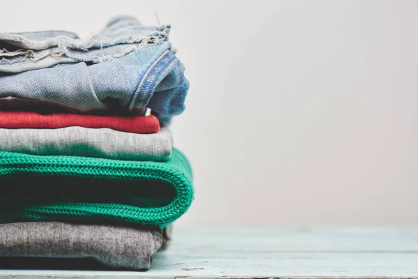 ファッショナブルな服セーターやジーンズ木製の背景の山 — ストック写真