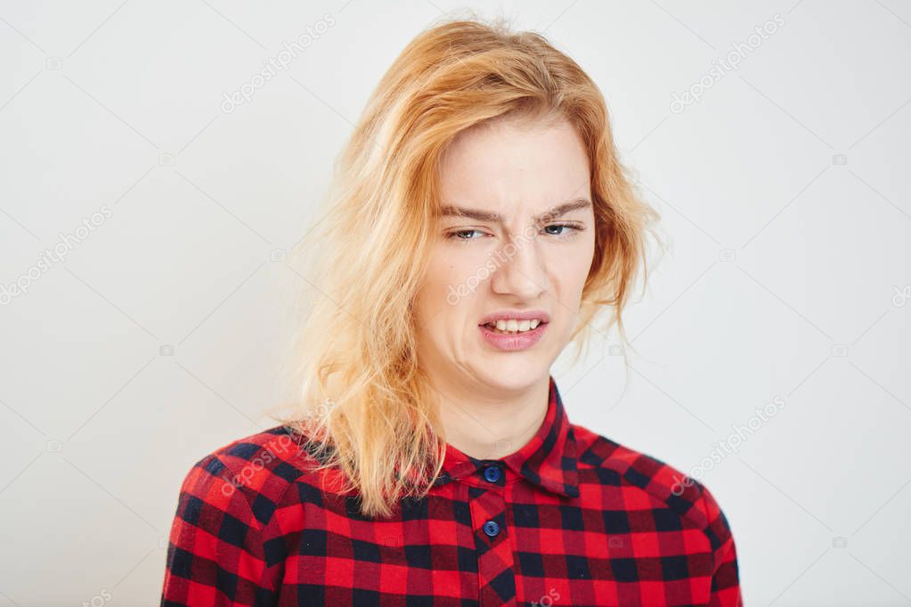 beautiful woman in checkered shirt showing emotion of disgust isolated on white background 