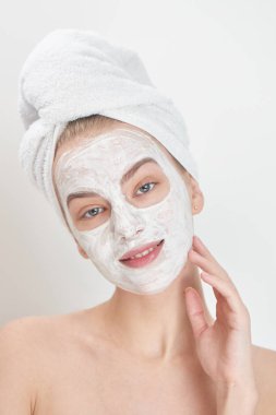 kafa havluya ve gülümseyen ve kameraya, spa konsept seyir yüzünde maske olan kadın portresi