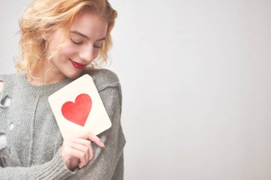 sevimli genç kadın kart kırmızı kalp ile gri arka plan üzerinde Sevgililer günü kavramı holding kazaklı