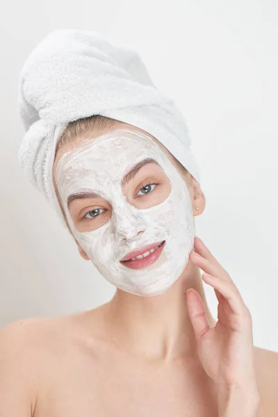 portrait of woman with towel on head and mask on face smiling and looking at camera, spa concept