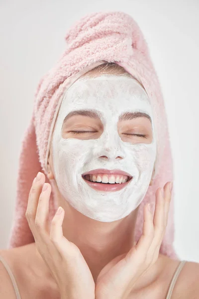 满意的女人戴着毛巾在头上闭着眼睛涂抹面膜 美容治疗理念 — 图库照片
