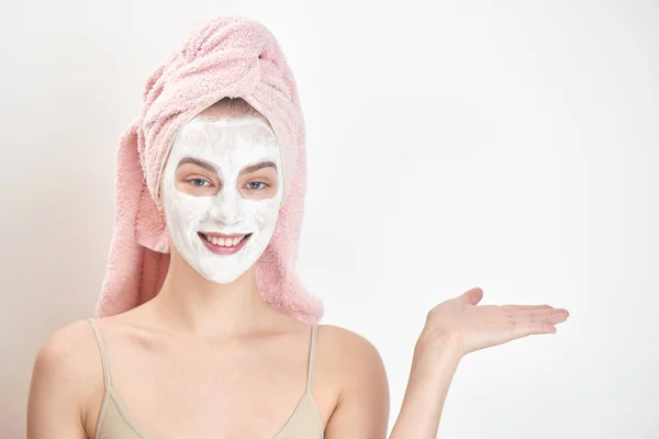 美丽的妇女与毛巾头上和面具在脸上指向右侧 皮肤护理概念 — 图库照片