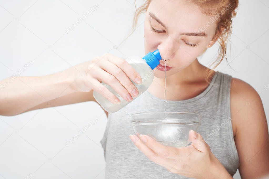 woman holding glass bowl and washing out nose with saline, Treatment and prevention of the common cold 