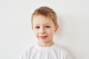 Kameraya bakarak ve beyaz stüdyo arka plan üzerinde poz beyaz t-shirt küçük çocuk portresi