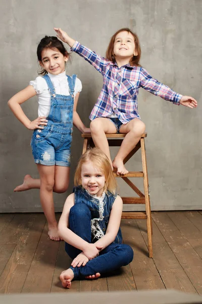 Three Girls Wooden Chair Posing Concrete Wall Background — Stock Photo, Image