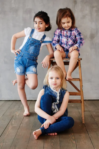 Three Girls Wooden Chair Posing Concrete Wall Background — Stock Photo, Image