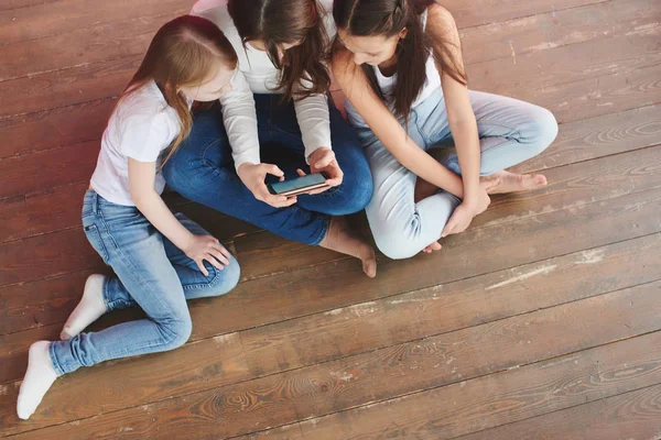 Three Teenage Girls Playing Games Phone While Sitting Wooden Floor — Stock Photo, Image