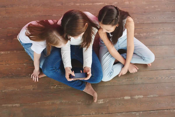 Three Teenage Girls Playing Games Phone While Sitting Wooden Floor — Stock Photo, Image