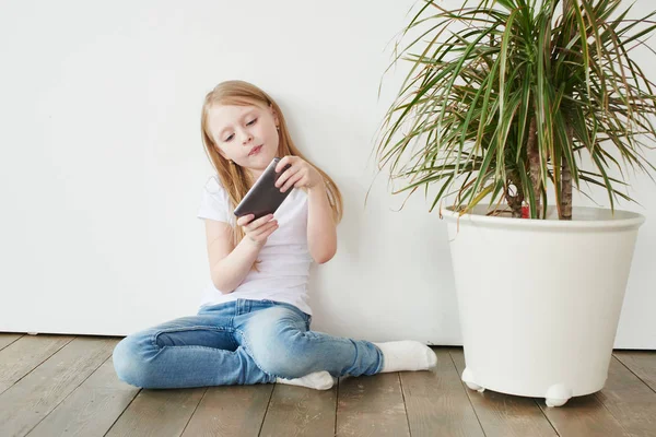 Little Blonde Girl Playing Phone While Sitting Wooden Floor White — Stock Photo, Image