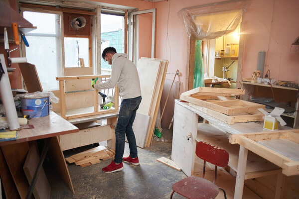 Young man working with wood while doing repairs in apartment 