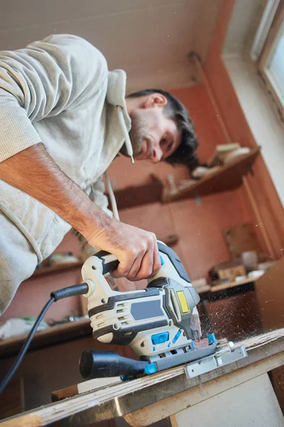 Νεαρός Άνδρας Που Εργάζεται Ηλεκτρική Σέγα Ενώ Πριονίζετε Κόντρα Πλακέ — Φωτογραφία Αρχείου