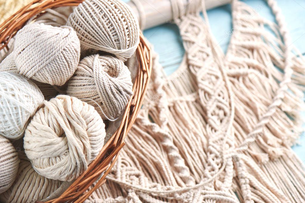 macrame threads in basket on wooden background, close-up