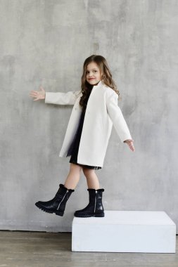sevimli küçük kız çocuk lookbook kavramı poz Studio gri duvar arka plan üzerinde beyaz ceket 