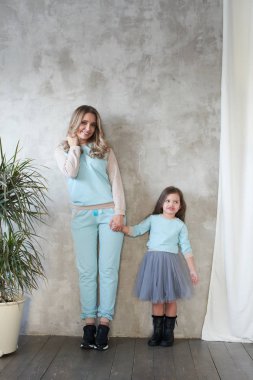 Anne ve kızı aynı giysileri studio, lookbook kavramı poz sırasında elele  