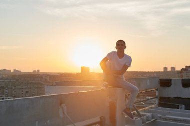 Bina, parkour kavramı çatı oturma rahat giyimli adam 