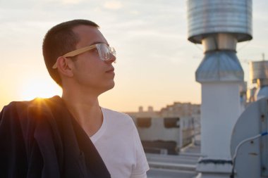 cityscape arka plan üzerinde çatı üzerinde beyaz t-shirt ayakta giyen yakışıklı adam 