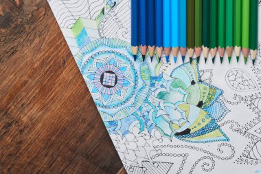coloring page with pencils in blue and green colors on wooden table , close-up  clipart