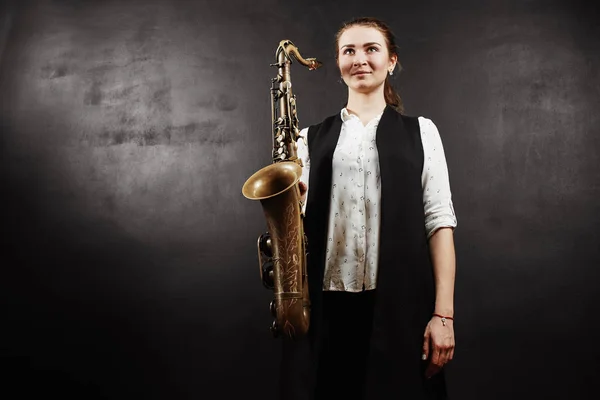 woman holding saxophone on black background