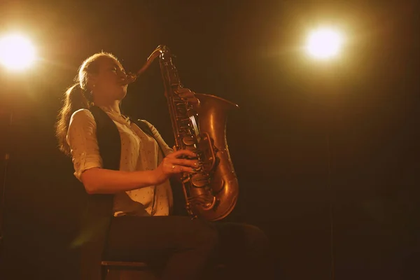 beautiful woman playing saxophone on stage