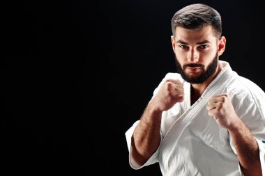 Beyaz kimono kamera duruş mücadelede dururken bakarak erkekte ciddi karate 