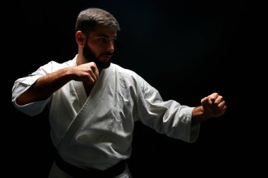 yan bakış beyaz ana karate giyen kimono koyu arka plan üzerinde poz duruş mücadelede