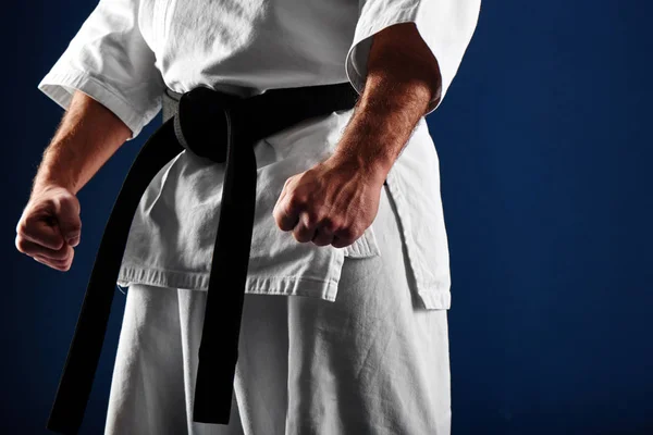 hands clenched in fists of man in kimono on blue background