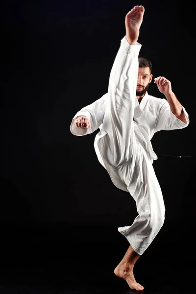Karate Hombre Kimono Golpeando Pie Sobre Fondo Negro — Foto de Stock
