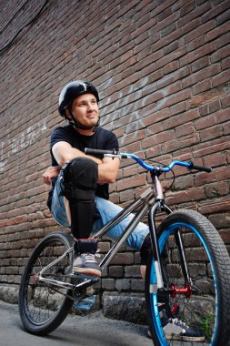 bina tuğla duvarına yakın çapraz silah ile bisiklet üzerinde oturan adam 